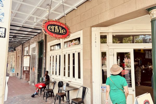 A street view shows the exterior of a café named "envie," with people sitting outside on a brick sidewalk.