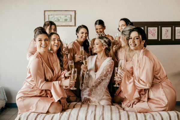 A group of women in robes are joyfully posing with champagne glasses, likely celebrating a special occasion.